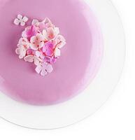 roze mousse taart met spiegel glazuur versierd met bloemen foto