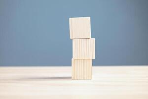 hout leeg drie blokken stack Aan tafel en blauw blackground met kopiëren ruimte voor tekst of symbolen, ontwikkeling concept voor groei succes werkwijze. foto