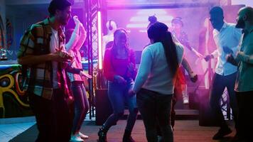 vrouw danser feesten Bij nachtclub, tonen funky dans beweegt Aan elektronisch muziek- Bij feest. jong mensen hebben pret samen met disco lichten Aan dans vloer, viering. handheld schot. foto