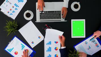 hoog hoek visie van bedrijf mensen in conferentie kamer met groen scherm chroma sleutel tablet Aan kantoor tafel. collega's hebben vergadering analyseren financieel statistieken grafieken planning De volgende project. foto