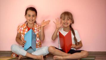 weinig meisjes lezing een boek in leven kamer. slim schoolmeisjes aan het doen hun huiswerk na school. onderwijs en afstand aan het leren voor kinderen. thuisonderwijs gedurende quarantaine. blijven Bij huis amusement. foto