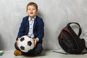 een weinig schooljongen, aan het studeren . een mannetje kind zittend Aan de vloer. foto