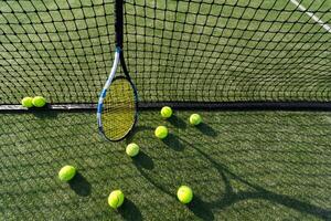 tennis racket aan het liegen Aan netto met tennis bal in moeilijk oppervlakte rechtbank foto