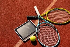 hoog hoek visie van tennis racket en bal door digitaal tablet Aan kastanjebruin achtergrond foto