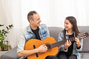 artistiek getalenteerd meisje tonen haar Latijns muziek- leraar de nieuw lied ze geleerd naar Speel Aan de akoestisch gitaar Bij huis foto