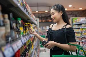 jong vrouw binnen een op te slaan op zoek Bij een Product en lezing de label. persoon kiezen groenten en fruit en boodschappen doen in supermarkt foto