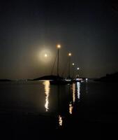 een boot is in de water Bij nacht foto