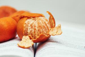dichtbij omhoog van een mandarijn Aan een Open boek foto