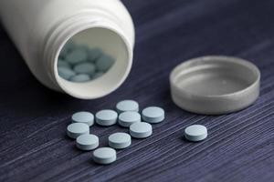 medicatie fles en blauwe pillen gemorst over blauwe houten achtergrond. farmaceutische medicijnen. foto
