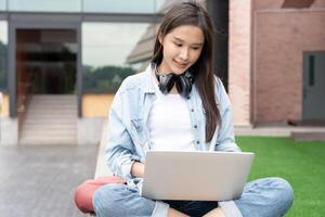 mooi Aziatisch vrouw vrouw leerling opgewonden controle taal test resultaten Aan laptop. glimlach meisje gelukkig studie online. boek in college campus. portret vrouw Aan Internationale Azië Universiteit. foto