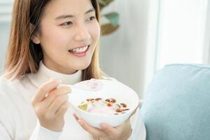 gezond voedsel. mooi vrouw meisje genieten eten yoghurt, muesli, vers fruit Aan ontbijt Gezondheid in huis. gelukkig jong vrouw glimlach Aan ochtend- mooi zo emotie. diëten, ontgiften, eetpatroon, schoon eten, vegetarisch foto