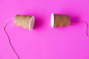 diy papier cups met draad Aan roze achtergrond. concept, telefoon speelgoed. concept, telefoon speelgoed welke van toepassing zijn met wetenschap kennis over trillingen geluid door uitpersen strings veroorzaken ons naar horen. foto