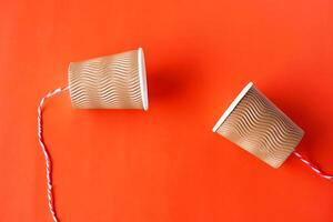 diy papier cups met draad Aan rood achtergrond. concept, telefoon speelgoed. concept, telefoon speelgoed welke van toepassing zijn met wetenschap kennis over trillingen geluid door uitpersen strings veroorzaken ons naar horen. foto