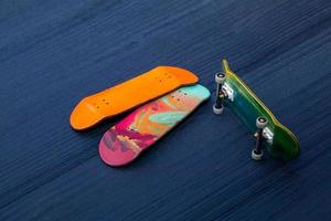 toets. een klein skateboard voor kinderen en tieners om met handvingers te spelen. op blauwe houten achtergrond foto
