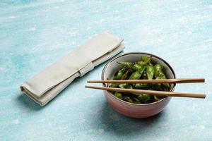 gekookte edamame op een blauw tafelblad. snack soja peulen