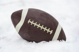 een Amerikaans voetbal gedekt met sneeuw en houdende in de sneeuw foto