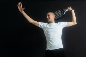 padel tennis speler met racket in hand. peddelen tennis, Aan een zwart achtergrond. foto