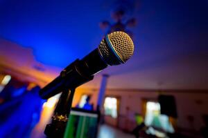 professioneel microfoon Aan een stadium met een wazig achtergrond. modern mic in de sprekend conferentie hal of congres kamer binnenshuis. detailopname foto