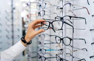 rij van bril Bij een opticiens. bril winkel. staan met bril in de op te slaan van optiek. vrouw kiest bril. gezichtsvermogen correctie. foto