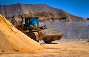 zand groeve, opgraven apparatuur, bulldozer met hoop van zand in achtergrond. selectief focus. foto