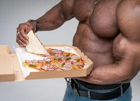 atletisch gespierd Mens nemen stuk van pizza van doos. knap Mens met naakt torso tonen heerlijk pizza. sexy koerier foto