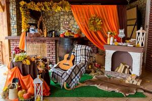 herfst landelijk fotozone. samenstelling met pompoenen en bladeren in de buurt muur. gitaar, oranje kleding en pompoenen. fotozone. foto