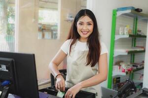 Indonesisch vrouw Kassa is werken met contant geld registreren veranderen geld Bill Bij supermarkt. foto