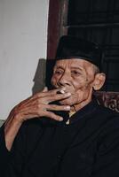 portret van een ouderen Aziatisch Mens roken een sigaret. foto
