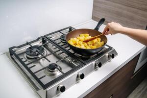 Koken gebakken aardappelen. frituren aardappelen Aan de frituren pan foto