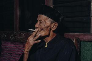 portret van een ouderen Aziatisch Mens roken een sigaret. foto