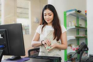 Indonesisch vrouw Kassa is werken met contant geld registreren veranderen geld Bill Bij supermarkt. foto