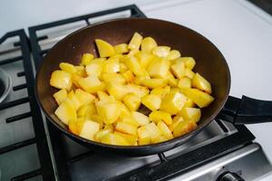 Koken gebakken aardappelen. frituren aardappelen Aan de frituren pan foto