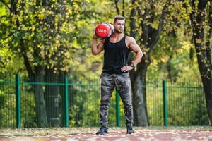 sterk mannelijk, buitenshuis geschiktheid werk. hijs- zwaar hulpmiddelen. knap sportman. jong bodybuilder. werken uit Aan een sportveld. zelfverzekerd Mens. foto