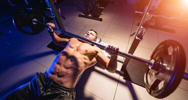 bodybuilder trainer Mens aan het doen bank druk op training in Sportschool. video van de top. blauw licht filter. naakt torso. sterk buikspieren. visie van bovenstaande. detailopname. foto