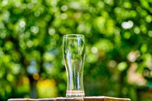 leeg glas van bier Aan houten tafel Aan groen natuur achtergrond foto