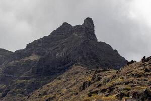 dramatisch rotsachtig berg top tegen een bewolkt lucht berg landschap met blauw lucht en wolken in tenerife. foto