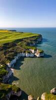 antenne visie van een robuust kustlijn met kliffen en een groen golf Cursus met uitzicht een sereen blauw zee in Flamborough, Engeland foto