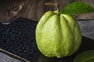 een groen fruit met bladeren Aan een houten tafel foto