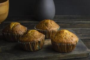 vier muffins zittend Aan een houten snijdend bord foto