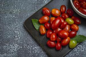 een kom van tomaten en bladeren Aan een zwart bord foto