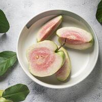 een kom van guava fruit met bladeren Aan een tafel foto