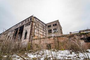 vernietigd verlaten fabriek na de oorlog, gebroken glas, verwoesting, beangstigend industrieel samenstelling foto