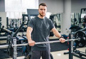 elegant knap trainer in modern Sportschool. aantrekkelijk jong Mens aan het wachten naar trein Bij Sportschool. foto