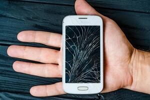 gebroken telefoon scherm in hand. gebroken glas van smartphone foto