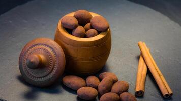 amandelen in zwart truffels. chocola truffel snoepjes met pinda's binnen en kaneel stokjes foto