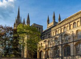 gotisch kathedraal met torenspitsen tegen een Doorzichtig blauw lucht, omringd door herfst gebladerte in peterborough, Engeland. foto