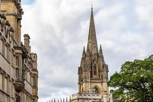 gotisch spits stijgt bovenstaand historisch gebouwen onder een bewolkt lucht, presentatie van bouwkundig erfgoed in Oxford, Engeland. foto