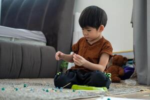 Aziatisch jongen spelen met plasticine in de kamer foto