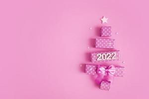 wenskaart met abstracte kerstboom gemaakt van geschenkdozen en nummers 2022 voor vrolijk kerstfeest en nieuwjaar foto