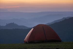 avonturier tenten gedurende 's nachts camping plaats Bij de mooi toneel- zonsondergang visie punt over- laag van berg voor buitenshuis avontuur vakantie reizen concept foto